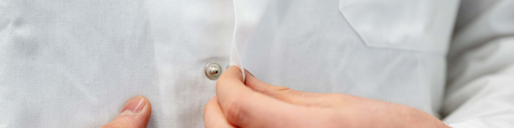 Ein Student schließt seinen Arbeitskittel