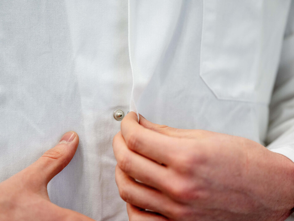 Ein Student schließt seinen Arbeitskittel